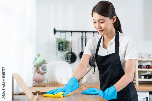 Asian young cleaning service woman worker clean kitchen table at home. photo