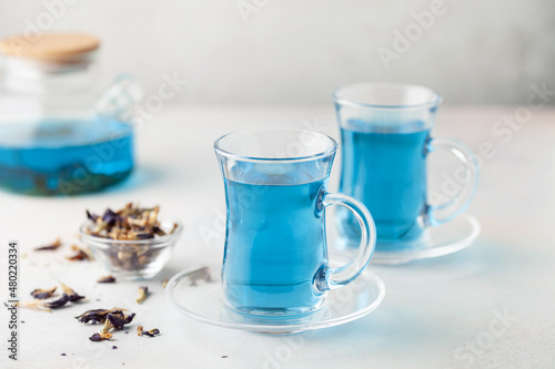 Thai blue Anchan tea in a glass cup and teapot on a wooden background.