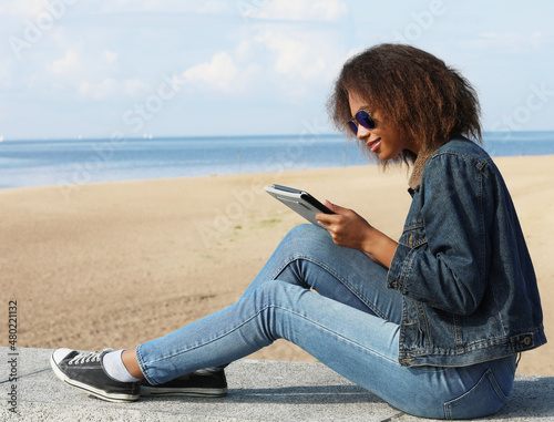 African american young woman with tablet on the beach