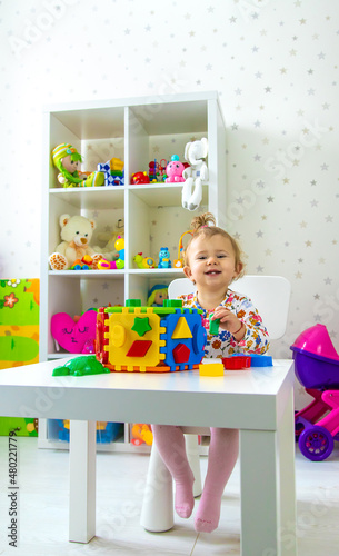 The child plays with toys in the room. Selective focus.