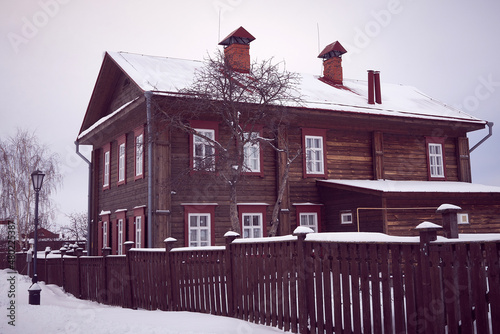 Vintage traditional wooden house with fence. Winter view.