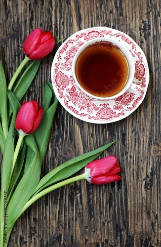 spring tea party. Tea in a beautiful tea pair porcelain and red tulips on a dark background. top view