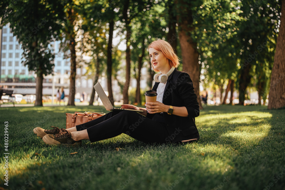 Pretty young caucasian woman go for a walk at park with coffe and laptop. Working outdoors Pretty young caucasian woman go for a walk at park with coffe and laptop. Working outdoors