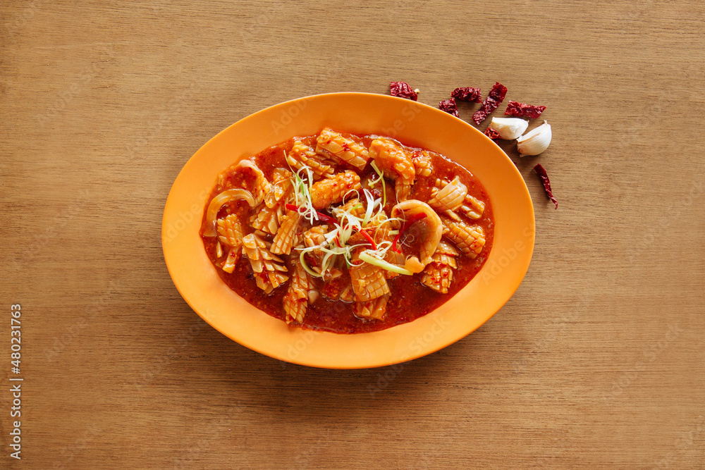 Cuttlefish with Satay Sauce in orange plate isolated on wood background top view Cuttlefish with Satay Sauce in orange plate isolated on wood background top view