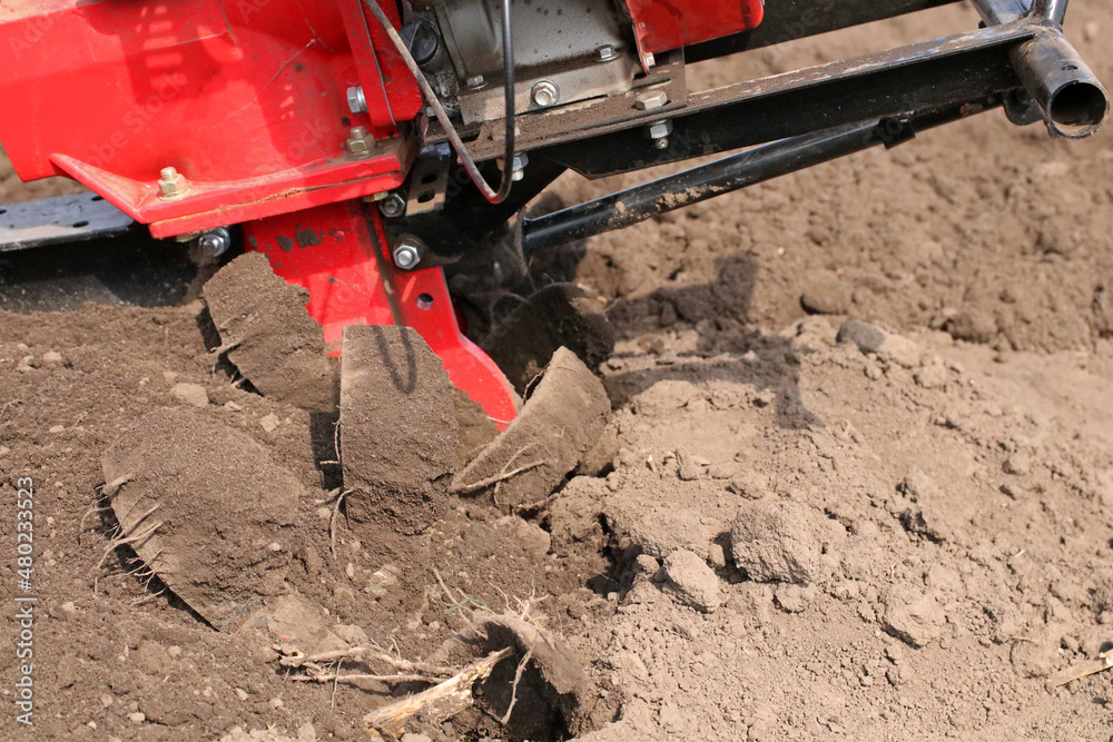 Garden tiller for cultivating field, loosens soil. Handheld motor plow