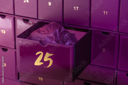 Violet advent calendar. In the advent calendar, cell number 25 is open, a Christmas present. A gift in wrapping paper inside an advent box.