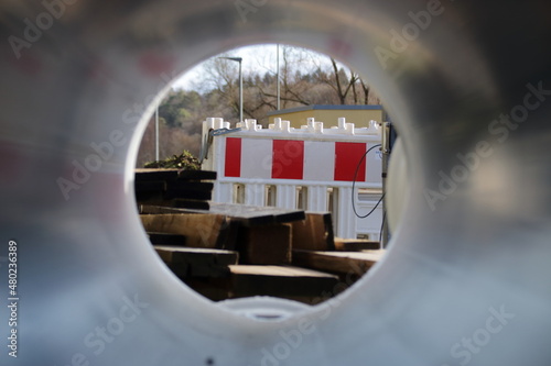 Blick durch ein Rohr auf Absperrmaterial auf einer Baustelle photo