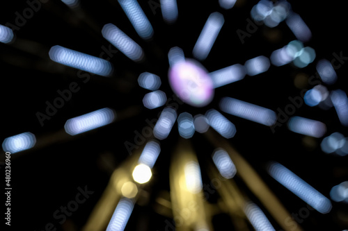 Defocused bokeh lights of Ferris Wheel at night market. Blurred fun bright and colorful background.