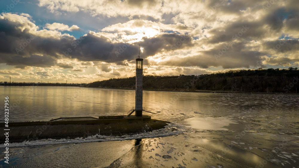 Aerial view of a pier with a lighthouse on a frozen lake