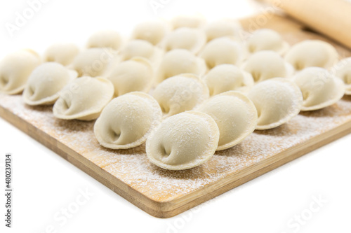 Raw dumplings on a wooden board. Traditional Russian food. White background.