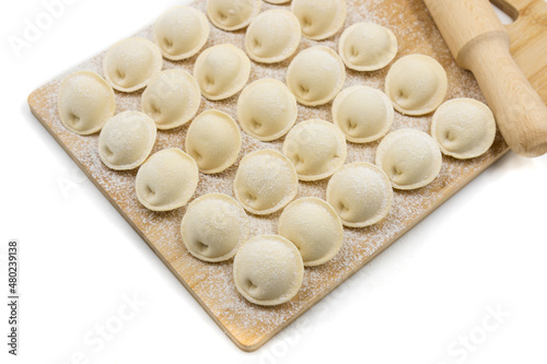 Raw dumplings on a wooden board. Traditional Russian food. White background. Top view.