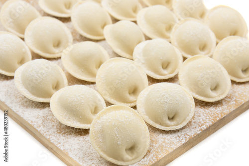 Raw dumplings on a wooden board. Traditional Russian food. White background. Close-up.