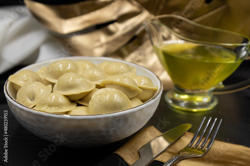 Boiled russian dumplings in a deep dish. Restaurant serving dishes. Black background.
