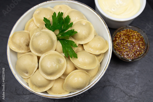 Boiled Russian dumplings in a deep dish. Top view. Black background.