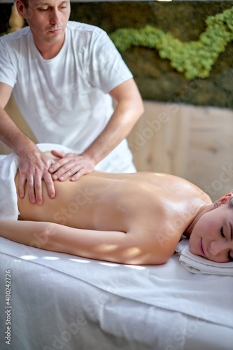 Good-looking young caucasian woman relaxing at spa center receiving back massage by professional masseur, relaxation recreation in luxury hotel resort, wellness beauty body care therapy health