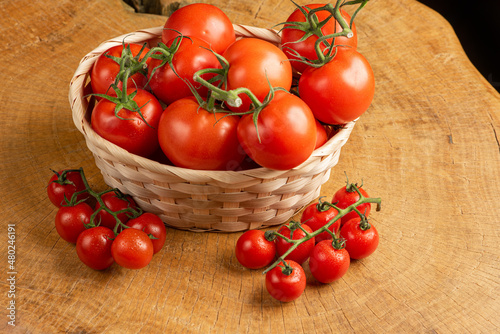 Tomatoes, beautiful tomatoes in a straw basket, over rustic wood, selective focus.