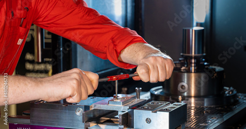 Engineer finishing a metal component that has been milled on a CNC machine 