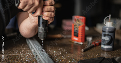Technician drilling hole in metal bracket to carry out repairs