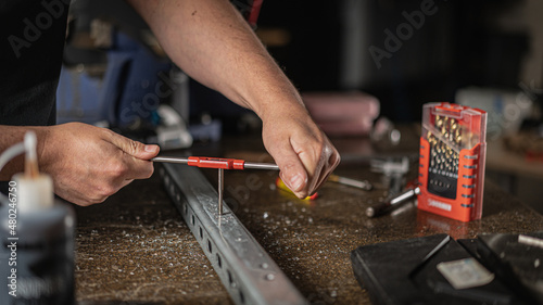 Technician repairing a metal bracket with hand tools