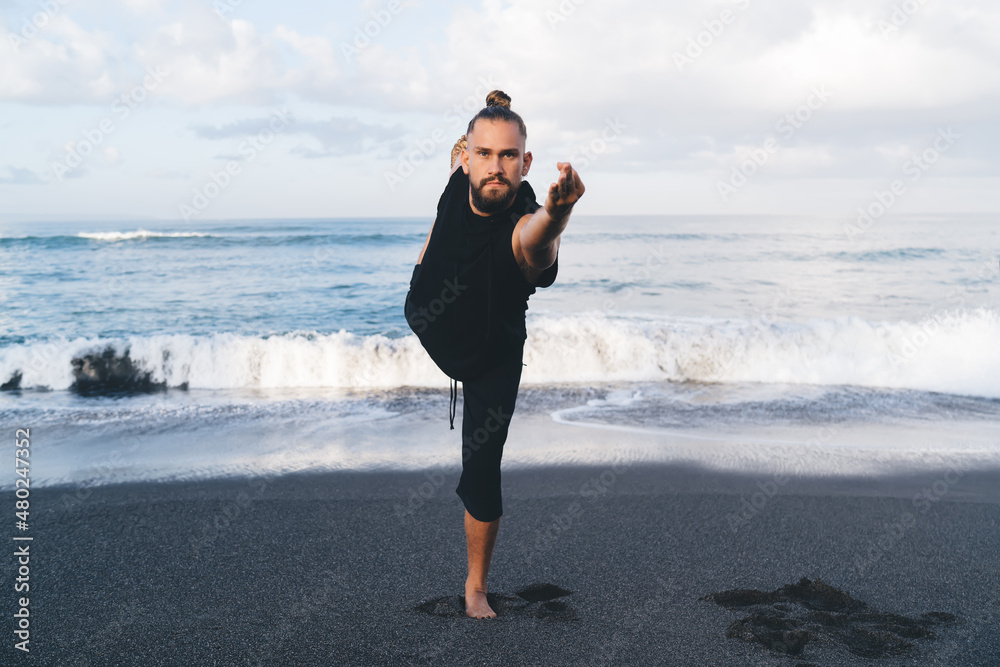 Caucasian man athlete with perfect pumped up figure recreating doing yoga poses feeling inner peace and vitality, male with flexible body standing in asana care about physical and mental health