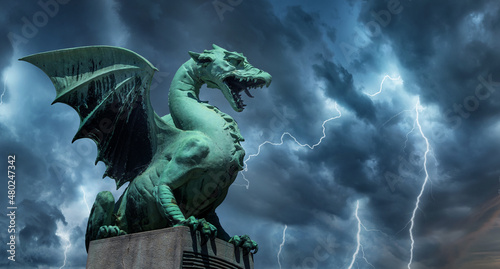  View of the Dragon bridge (Zmajski most), symbol of Ljubljana, capital of Slovenia, Europe. Sculpture of a dragon against a dark stormy sky. photo
