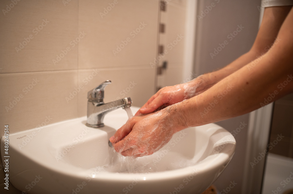 a man is washing his hands in a home bathroom a man is washing his hands in a home bathroom