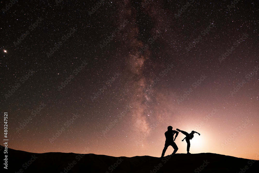 Silhouettes of karate fighters on the background of the starry sky. Beautiful milky way galaxy. Night scenne. Silhouettes of karate fighters on the background of the starry sky. Beautiful milky way galaxy. Night scenne.