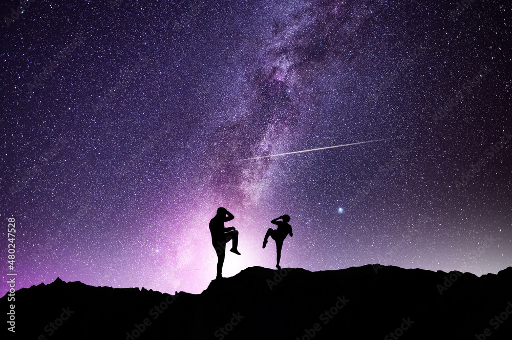 Fototapeta premium Silhouettes of karate fighters on the background of the starry sky. Beautiful milky way galaxy. Night scenne.