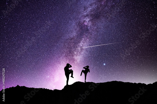 Silhouettes of karate fighters on the background of the starry sky. Beautiful milky way galaxy. Night scenne.