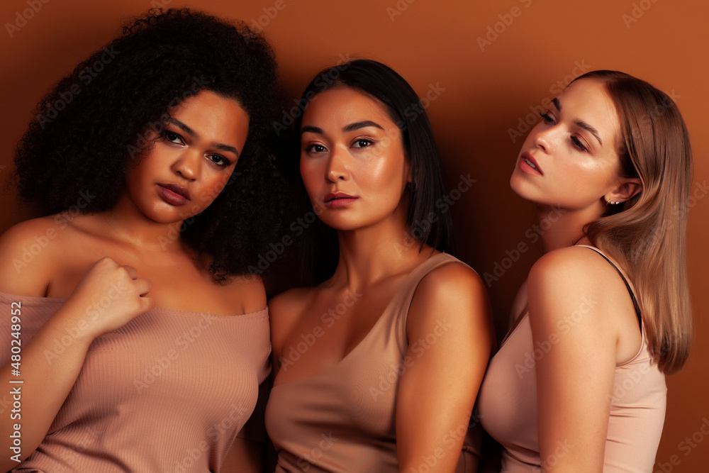 young pretty asian, caucasian, african woman posing cheerful together on brown background, lifestyle diverse nationality people concept young pretty asian, caucasian, african woman posing cheerful together on brown background, lifestyle diverse nationality people concept