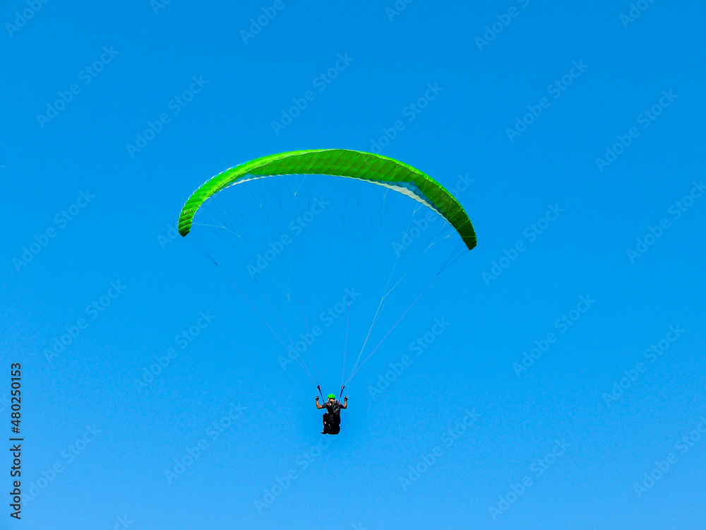 Para glider soars over the beach, waves and hills at Murawai Beach, Auckland, New Zealand Para glider soars over the beach, waves and hills at Murawai Beach, Auckland, New Zealand