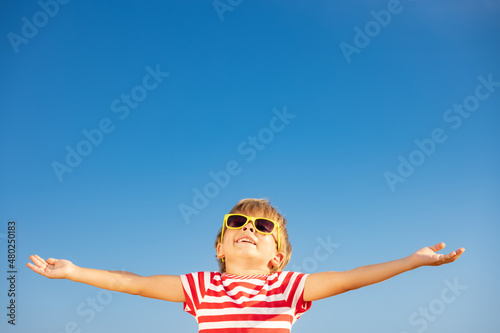 Happy child having fun outdoor against blue sky