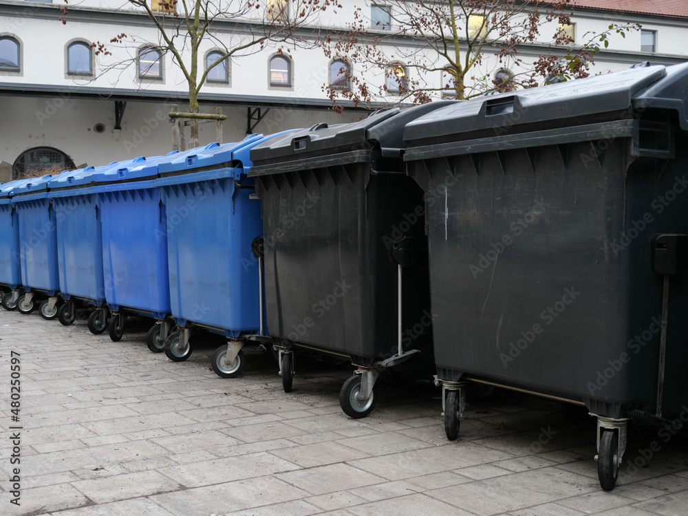 Eine Reihe von Müllcontainern für Papiermüll und Restmüll in einem Hof Eine Reihe von Müllcontainern für Papiermüll und Restmüll in einem Hof