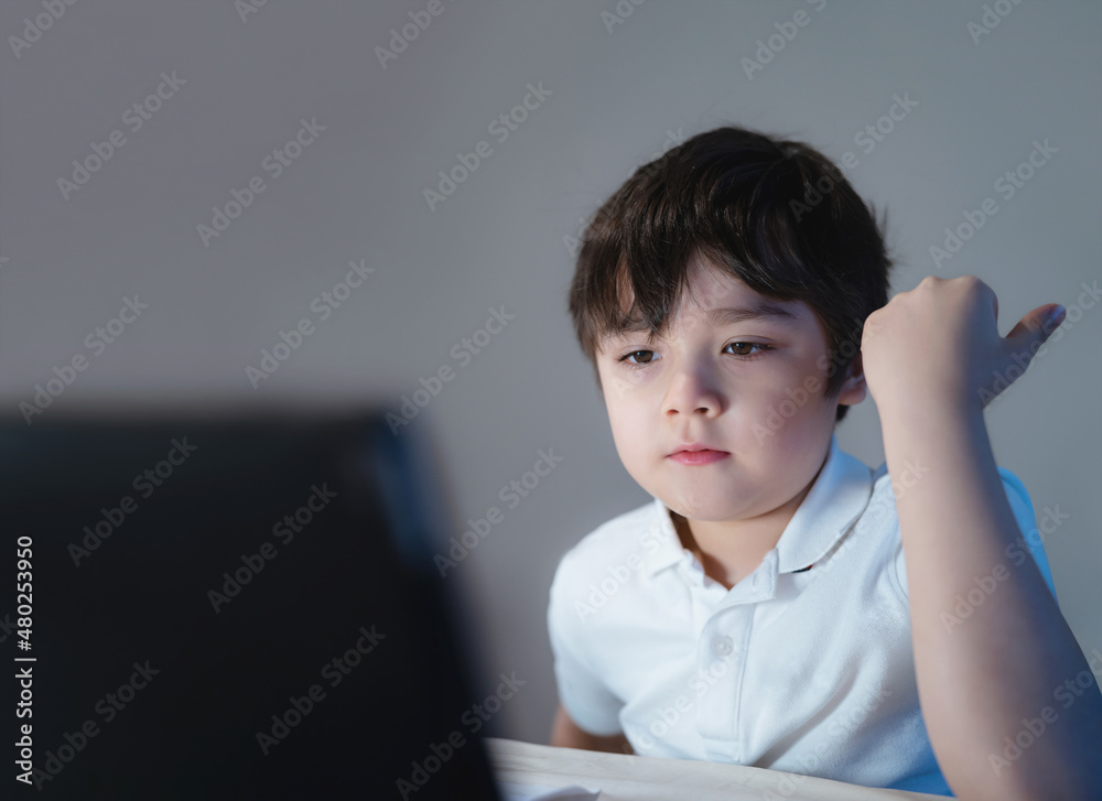 Happy school kid having fun watching cartoon on tablet, Child using digital pad searching the ideas on internet for his homework, Home schooling, Home learning or E-learning online education Happy school kid having fun watching cartoon on tablet, Child using digital pad searching the ideas on internet for his homework, Home schooling, Home learning or E-learning online education
