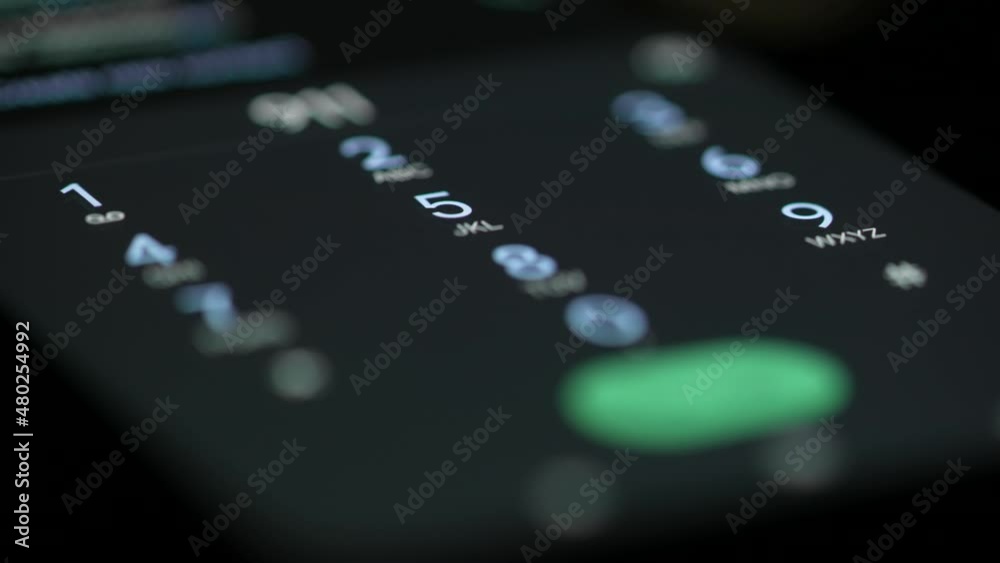 Female finger dials the phone number on the touchscreen of the smartphone. The woman touches the number icons and then presses the call button, an outgoing call. Close up.