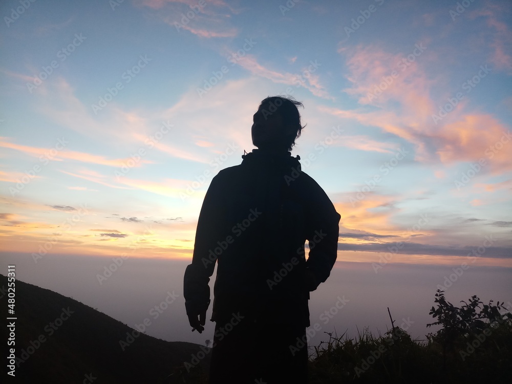 silhouette of man standing on top of mountain INDONESIA silhouette of man standing on top of mountain INDONESIA