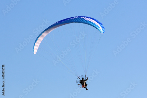 Paramotor pilot flying in a blue sky 
