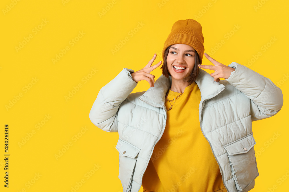 Cool young woman in stylish warm clothes on color background