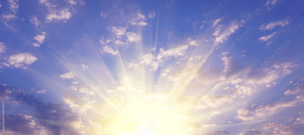 A blue sky with white clouds with golden sunlight shining naturally in the morning for a background or illustration.