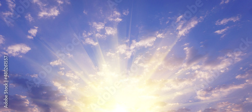 A blue sky with white clouds with golden sunlight shining naturally in the morning for a background or illustration.