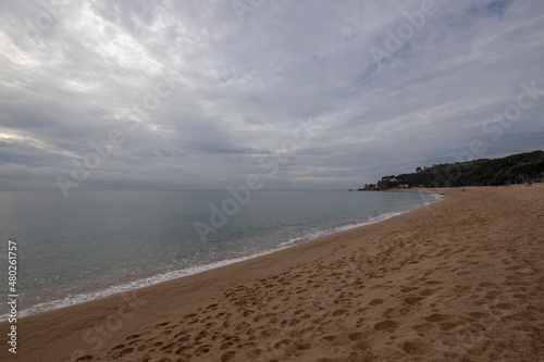 Sandy coast and stones under a cloudy sky on the Costa Brava, Spain. Picturesque seascape with a coast.
