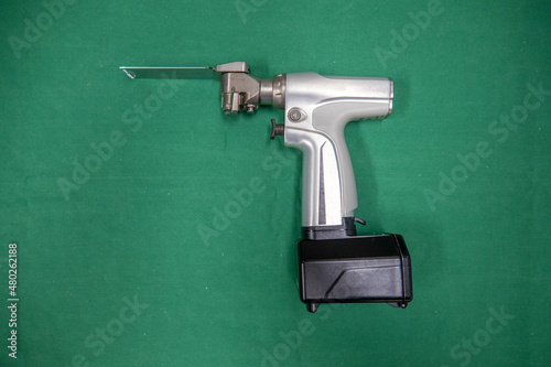 Obraz na płótnie a battery powered surgical oscillating saw with saw blade lies on a green surgical drape w salonie
