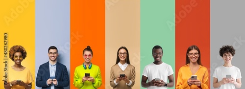 Group portrait of smiling multiethnic young people holding phones, isolated on multicolored background