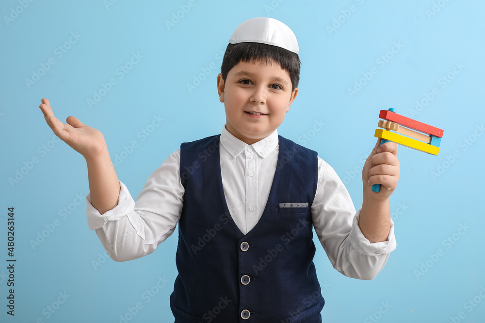 Little Jewish boy with gragger for Purim holiday on color background Little Jewish boy with gragger for Purim holiday on color background