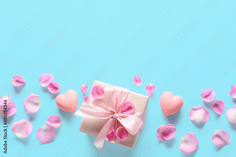 Composition with gift box for Valentine's Day, rose petals and hearts on color background