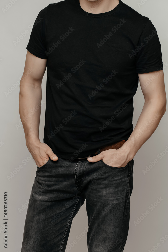 Obraz premium brutal attractive man poses in a black empty T-shirt made of thin premium cotton, highlighted on a white mock-up