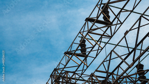 Electrical power substation with power lines and insulators on a blue sky background.