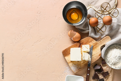 Wooden board with butter and ingredients for preparing chocolate brownie on beige background