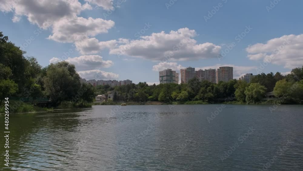 Pond with green water among lawns and trees against buildings of city. Pond with green water among lawns and trees against buildings of city.