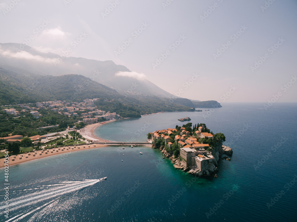 Yacht sails to the island of Sveti Stefan, leaving a foamy trail